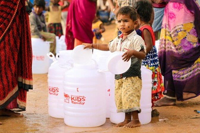 Providing drinking water to the slums kid inserting the lid to a water carboy